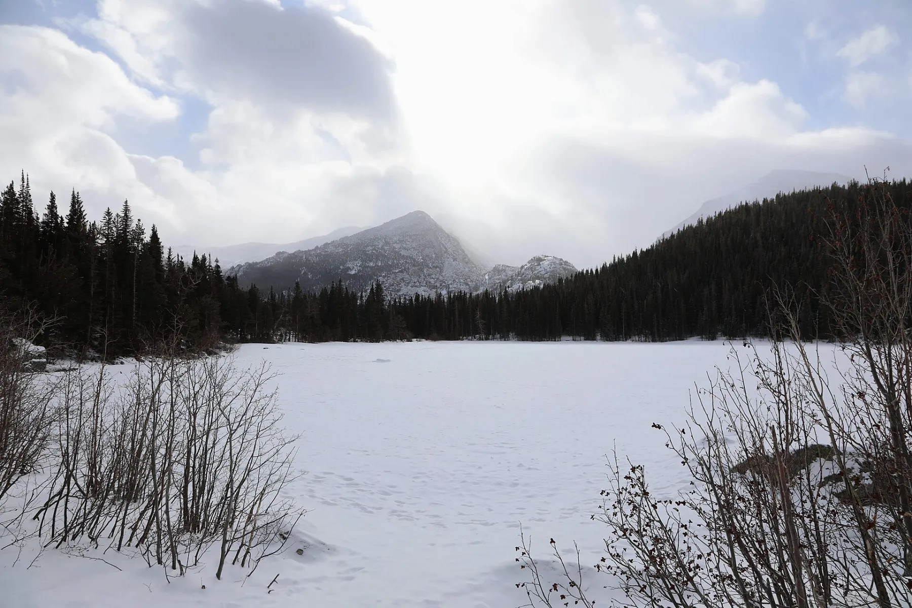 Snow-covered Bear Lake with mountains and evergreen forest under a bright winter sky